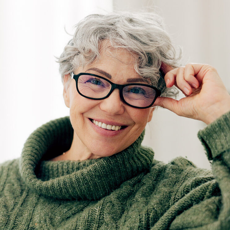 Happy, face and senior woman on sofa to relax in home or grandma laughing with happiness and freedom in retirement. Portrait, elderly person and smile in living room, house or thinking of good memory